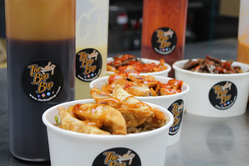 Various bowls of noodles from our menu and sauces in the background